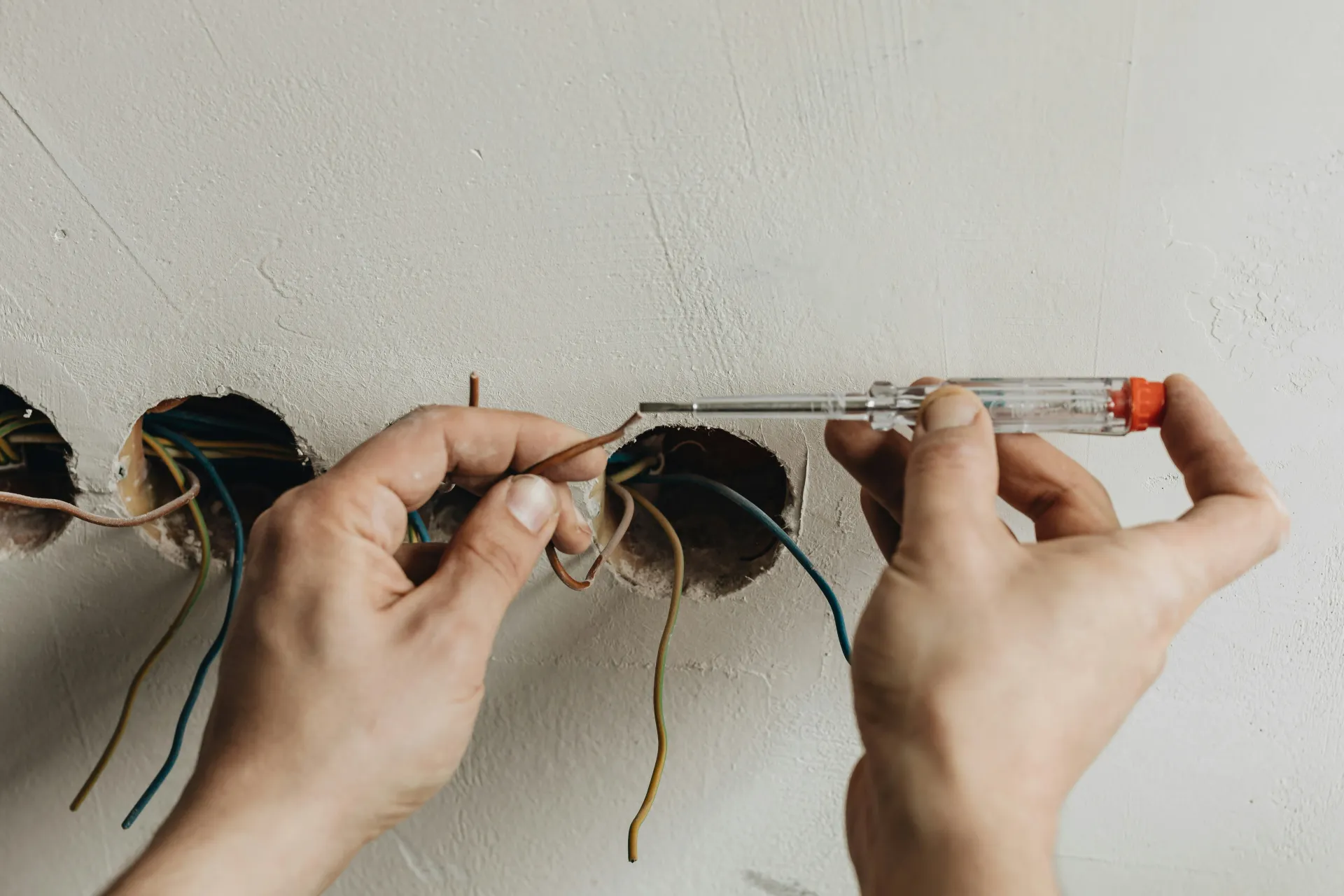 Close-up of an electrician connecting electrical wiring for new sockets in a wall.
