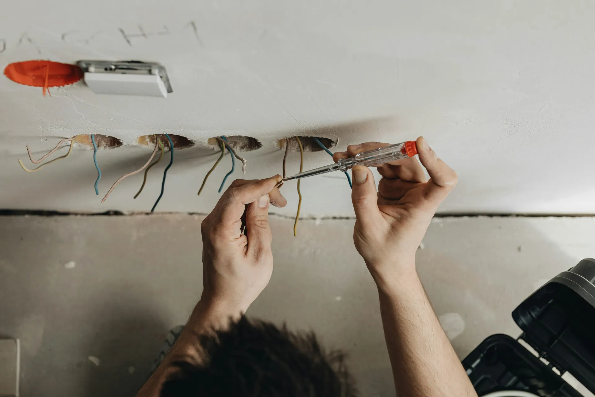 Electrician testing electrical wires in a wall for new socket installation or rewiring