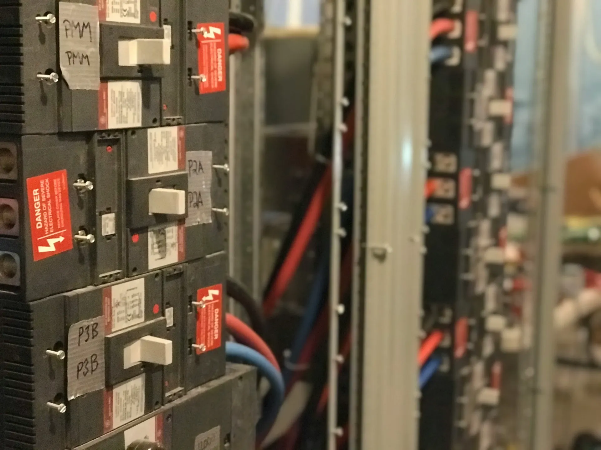 Industrial electrical panel with robust circuit breakers, safety warning labels, and three-phase wiring.